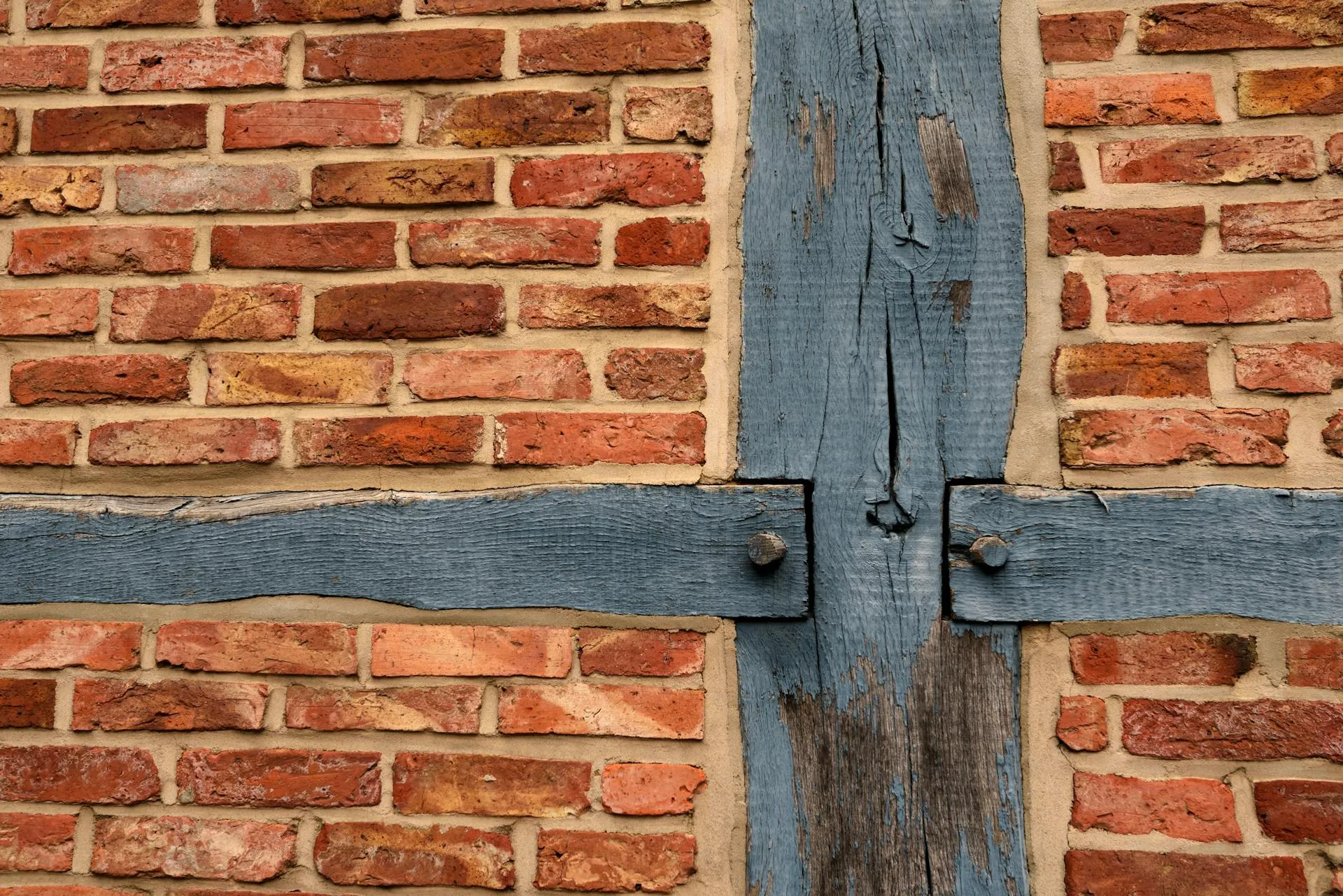 Historic timber-framed brick wall showing structural timber and brickwork interface where reticulation systems install